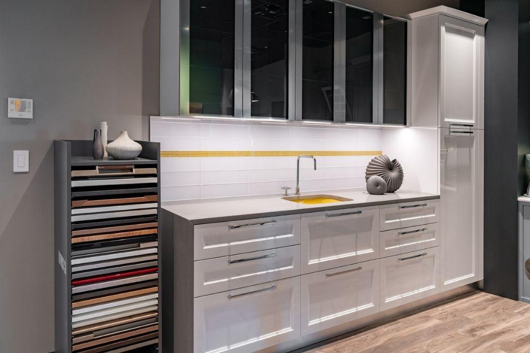 View of a sample counter space in Interiology 展厅 with cabinets featuring sleek grays contrasted with white tile and yellow accents. 