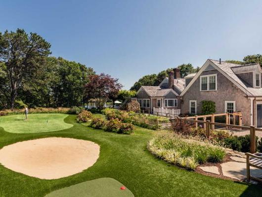 golf course with sand trap and person practicing next to a home